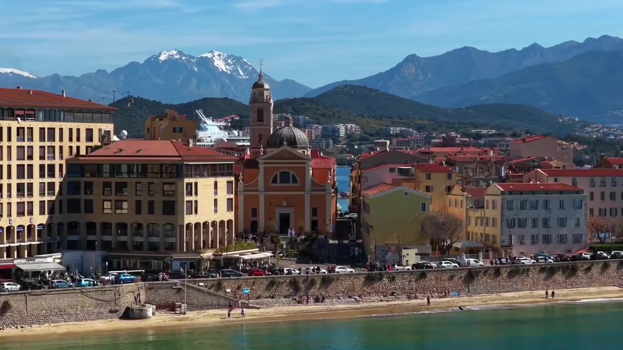 Aiacciu vue depuis la mer : la cathédrale, le front de mer et les montagnes enneigées